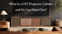 Modern living room with a UST projector cabinet beneath a large screen, introducing what a dedicated ultra short throw projector cabinet is.