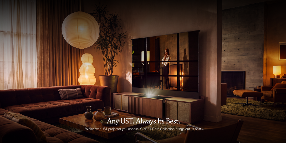 A modern living room featuring a CINEST UST projector cabinet with a projected image, warm ambient lighting, a brown sofa, and wood and concrete finishes